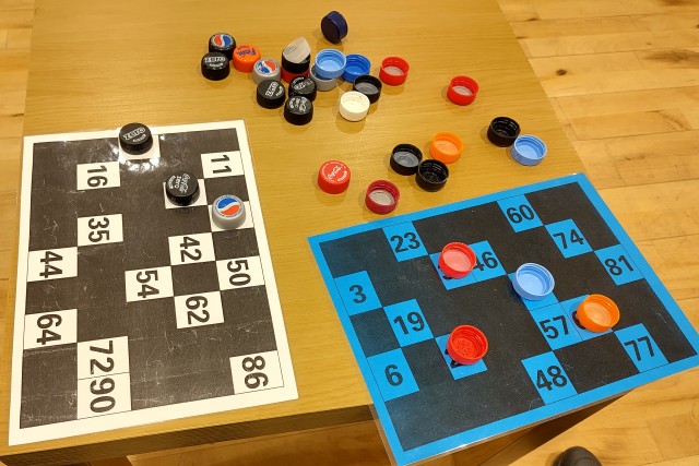 Two Bingo cards, with some bottle-top markers